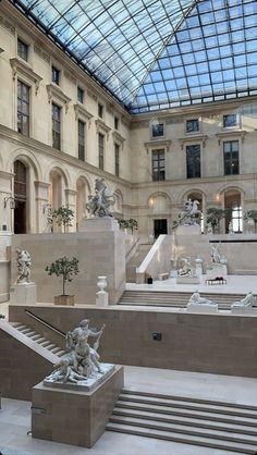 the inside of a building with many statues on display in front of glass roofing