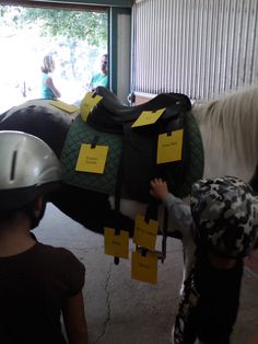 two children are standing next to a horse that is being held by another child with yellow sticky notes on it