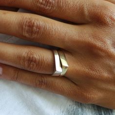 a close up of a person's hand with two wedding bands on their fingers