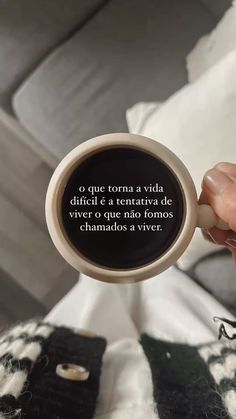 a person holding up a coffee cup with the words in spanish and english on it