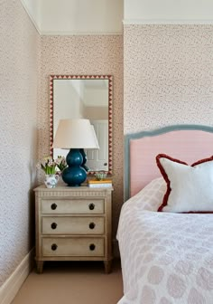 a bedroom with pink and blue decor on the walls, bed and dresser in front of mirror