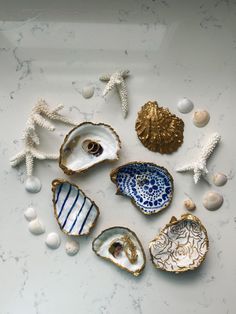 shells and seashells are arranged in a circle on a white surface with gold accents