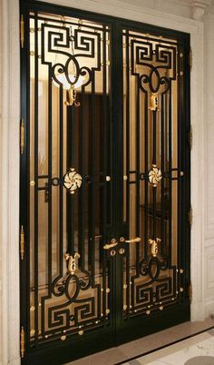 an ornate black and gold door in a white building with glass panels on the doors