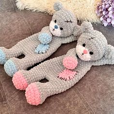 two crocheted teddy bears laying next to each other on a couch with flowers in the background