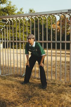 a young man leaning against a metal fence