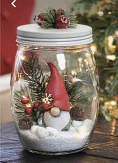 a glass jar filled with snow and christmas decorations