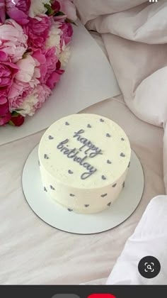 a birthday cake sitting on top of a white plate next to pink and white flowers