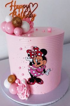 a pink birthday cake with minnie mouse on it