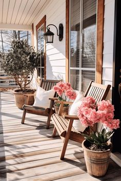 two wooden chairs sitting on top of a porch next to potted plants and flowers