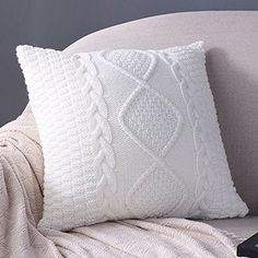 a remote control sitting on top of a couch next to a white knitted pillow