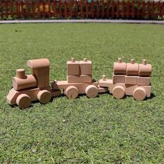 a wooden toy train sitting on top of a lush green field