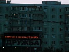 an apartment building is lit up at night with the word russian on it's side