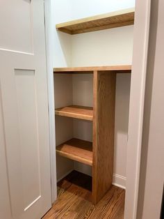 an empty closet with wooden shelves and white walls