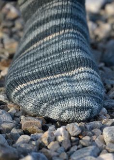 a person's feet with socks on and rocks in the foreground as if they were walking