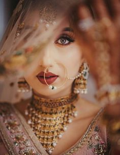 a woman in a bridal outfit with jewelry on her neck and hands behind her head