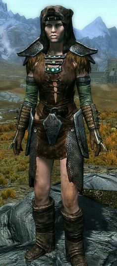 an image of a woman in armor standing on a rocky area with mountains in the background