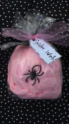 a pink bath bomb wrapped in plastic with a spider on it's side and a name tag