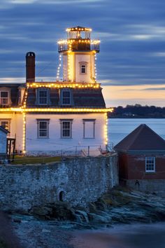 a lighthouse with christmas lights on it next to the ocean