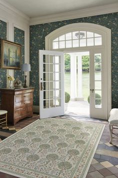 an ornately decorated entryway with french doors and rug on the floor in front of it