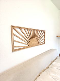 a bed with white sheets and a wooden sun decoration on the wall