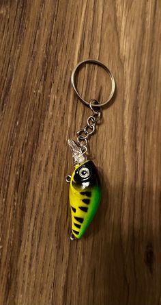 a yellow and green fish shaped keychain sitting on top of a wooden table