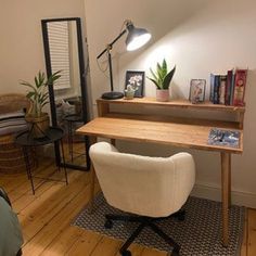 a room with a desk, chair and mirror on the wall next to a bed