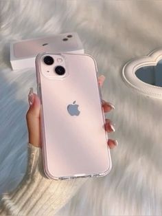 a woman's hand holding an iphone case in front of a white fur background