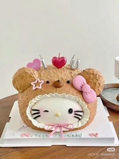 a cake shaped like a hello kitty head on top of a table with other items