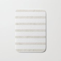 a white and gray striped bath mat on top of a table next to a cup