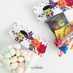 two bags filled with marshmallows and candy on top of a white table