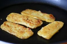 four pieces of fried food cooking in a frying pan