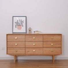 a wooden dresser sitting on top of a hard wood floor next to a white wall