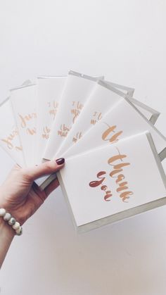 a hand holding five cards with gold foil on them, and the word love is written in cursive writing