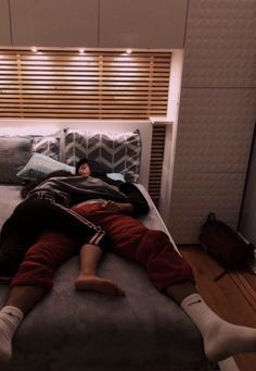 a man laying on top of a bed next to a wooden slatted wall