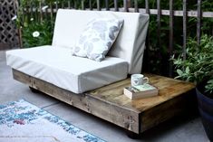 a white couch sitting on top of a wooden table next to a potted plant