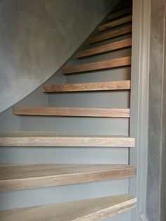 a set of wooden stairs leading up to a second story room with gray walls and wood flooring