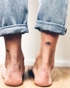 a person's foot with a small eye tattoo on their left ankle and the other leg