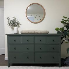 a green dresser with a round mirror above it