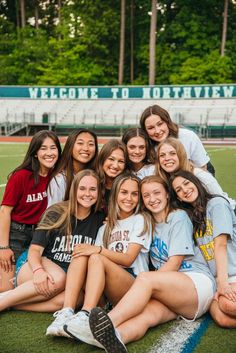 a group of young women sitting on top of a soccer field next to each other