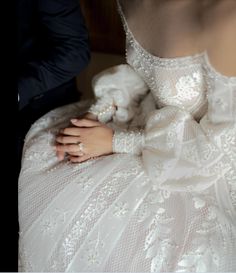 a woman in a wedding dress with her hand on the back of someone's shoulder