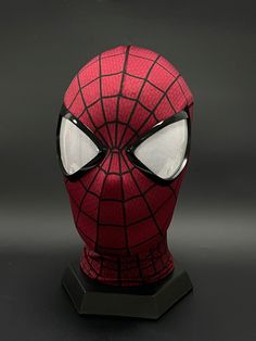 a close up of a spider - man mask on a black surface with white eyes