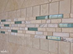 a tile wall with some green and white glass tiles on the bottom half of it