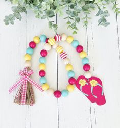 a wooden beaded bracelet with a pink flip flop on it and a flower pot next to it