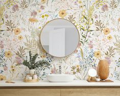 a bathroom with floral wallpaper and a round mirror