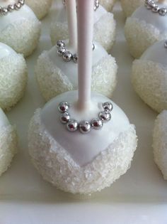 there are many white desserts with silver decorations on the top one has a candle in it