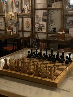 a chess board with pieces on it in a room filled with chairs and pictures hanging on the walls