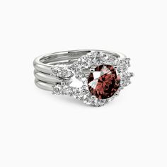 a white gold ring with an oval shaped garnet stone surrounded by round brilliant cut diamonds