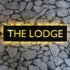 the lodge sign is lit up on a stone wall