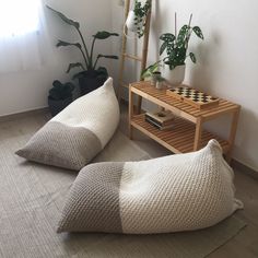 two bean bags sitting on top of a rug next to a wooden table and potted plants