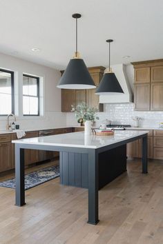 a kitchen with two pendant lights hanging from the ceiling and an island in the middle